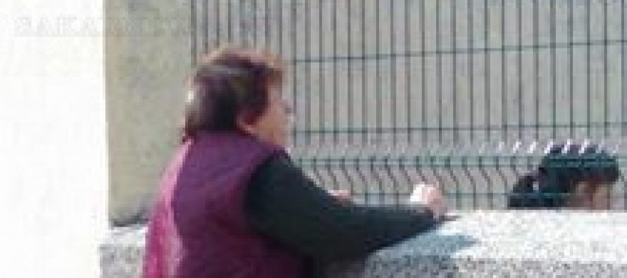 Възрастна жена търгува през ограда на Начално училище